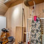 Raum mit Holzwänden, Kleiderständer, Staubsauger und Kinderstuhl.
