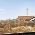 Haus mit rotem Dach und Leuchtturm im Hintergrund.
