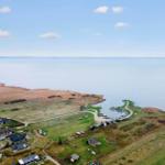 Aerial view of coastal village with houses, boats, and wide water.