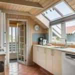 Küche mit Holzwand, Dachfenster und Blick auf Terrasse.
