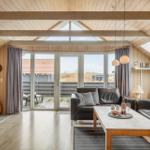 Wohnzimmer mit Holzdecke, Sofa, Kamin und Blick auf Terrasse.