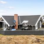 Moderne Ferienhaus mit großem Holzterrasse und Grillplatz im Freien.
