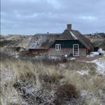 Haus mit Strohdach und Schnee auf Dünen