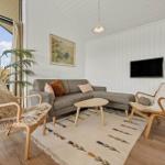 Wohnzimmer mit Sofa, zwei Stühlen, Teppich und Fernseher an der Wand.