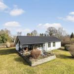 Moderne Villa mit großem Garten und Terrasse unter blauem Himmel.
