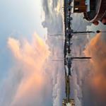 Bootshäuser und Segelboote am Hafen bei Sonnenuntergang.