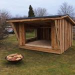 Holzkonstruktion mit Sitzbank und Kaminbereich im Freien.