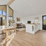 Moderne offene Küche mit Essbereich und Wohnzimmer. Holzfußboden und große Fenster.