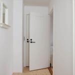 White doorway with wooden floor and mirror on the wall.
