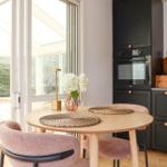 Round table with chairs, kitchen unit, and view to terrace with hanging chair.