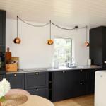 Kitchen with black cabinets, stainless steel sink, and gold pendant lights.