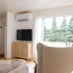 Living room with TV, armchair, and view of forest.