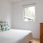 Bedroom with bed, window, and wooden dresser. Wall art and lamp are visible.