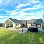 House with terrace, hot tub, and garden under blue sky.