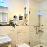 Badezimmer mit Dusche, Waschbecken und Spiegelschrank.