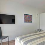 Schlafzimmer mit Bett, Fernseher, Kleiderschrank und Fenster