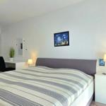 Schlafzimmer mit Bett, Nachttisch, Schreibtisch und Wandbildern.