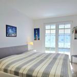 Schlafzimmer mit Bett, TV, Stuhl und Fenster zur Aussicht.