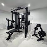 Fitnessraum mit Kraftstation, Bank und Hantelständer.