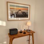 Holztisch mit Lampe, Kerzen und Lautsprecher unter einem Bild an der Wand.