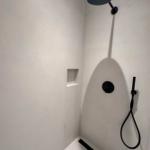 Dusche mit schwarzer Duschkopf und Handbrause, integrierte Ablage und schlichter Boden