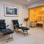 Zwei Holzstühle mit Kissen vor einer Sauna mit Glasfront.