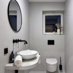 Badezimmer mit Waschbecken, Spiegel und Toilette.