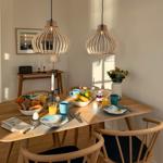 Esstisch mit vier Stühlen, zwei Hängelampen und Frühstücksausstattung.