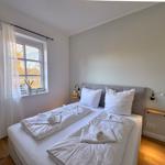 Schlafzimmer mit Doppelbett, Fenster und Holzboden.