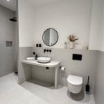 Moderne Dusche, Waschbecken und Toilette in minimalistischem Badezimmer.