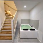 Eine Whirlpool-Badewanne neben einer Treppe mit Holzstufen und weißem Geländer.