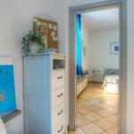 Bedroom with blue bed and dresser. Passage to another room with window and bed.