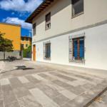 House with white walls and blue windows in courtyard