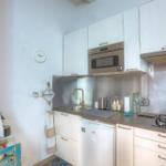 Kitchen with white cabinets, stove, sink, and microwave.