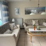 Wohnzimmer mit zwei Sofas, Glas-Tisch und Wandbildern.