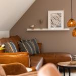 Ein Wohnzimmer mit braunem Ledersofa, hängenden Lampen und einem Tisch.