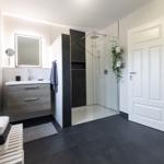 Badezimmer mit Dusche, Waschbecken und Heizung.