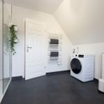 Badezimmer mit Dusche, Waschmaschine und Heizkörper