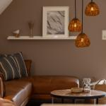 Wohnzimmer mit Ledersofa, runden Tisch und drei hängenden Lampen.