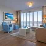 Terrasse mit Tisch und Stühlen, Blick auf Meer und Wiese.