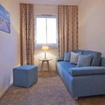 Zwei Betten mit blauen Kissen und Blick auf Balkon mit Meerblick.