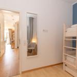 Schlafzimmer mit Bett, Wandbild, Lampe und Fernseher an der Wand.