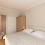 Schlafzimmer mit Bett, Fenster, Lampe und Wandbild.