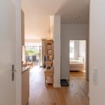 Zimmer mit Doppelbett, Sessel und Holzboden. Fenster mit Vorhängen.