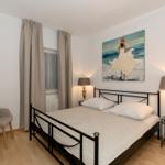 Ein Schlafzimmer mit Doppelbett, Stuhl und Fenster mit Vorhängen.