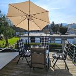 Terrasse mit Sonnenschirm und vier Stühlen. Blick auf Grünfläche und Gebäude.
