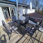 Terrasse mit vier Stühlen und Tisch. Hintergrund: Haus mit Satellitenschüssel und Dach.