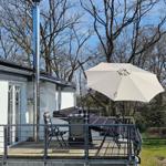 Terrasse mit Sonnenschirm und Sitzgelegenheiten. Hintergrund: Bäume und Haus.