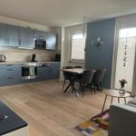 Küche mit Essbereich und Wohnzimmer mit Holzboden und grauer Einbauküche.