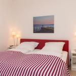 Schlafzimmer mit Bett, Nachttischen und Wandbild.